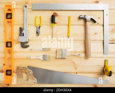 Werkzeuge, die auf einer Holzoberfläche für Heimwerkerprojekte angeordnet sind, einschließlich Hammer, Säge und verschiedenen Messgeräten Stockfoto