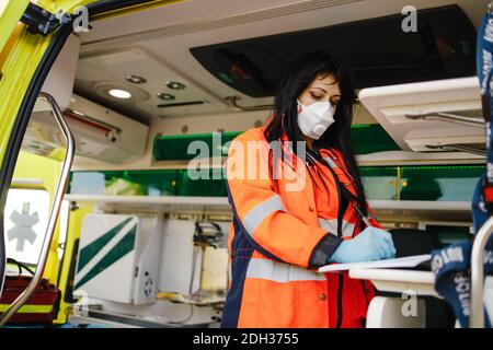 Junge weibliche Sanitäterin füllt Dokumente im Krankenwagen Stockfoto