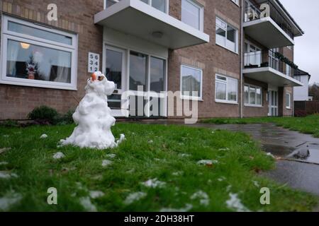 Kleiner hässlicher Schneemann, der im Garten eines kleinen Wohnhauses in Cambridge schmilzt. Der erste Schnee der 2020 Jahre und die Kinder haben Spaß beim Erstellen Stockfoto