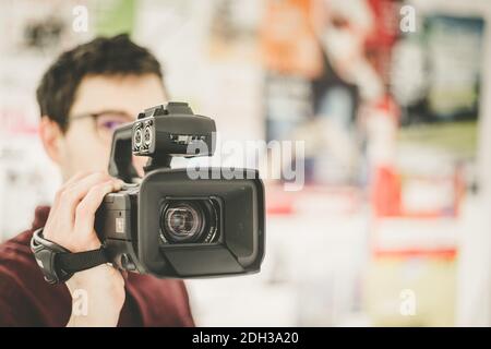 Professionelle Filmproduktion: Männlicher Filmemacher zeichnet mit einer professionellen Filmkamera auf. Nahaufnahme des Kameraobjektivs. Stockfoto