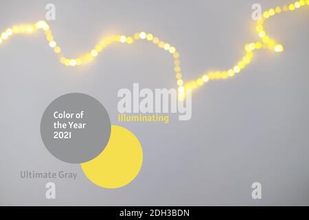 Demonstration der trendigen Farben 2021 - Grau und Gelb. Defokussierte Glitzerlampe auf monochromem Hintergrund mit Kopierbereich Stockfoto