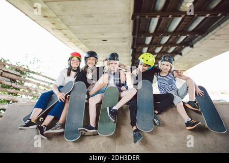 Gruppe von Freunden Kinder auf Skate Rampe. Porträt von selbstbewussten frühen Teenager-Freunden, die im Freiluftstadtskate-Park herumhängen. Leuchtet Stockfoto