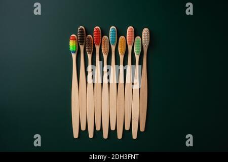 Ein Set umweltfreundlicher antibakterieller Zahnbürsten aus Bambusholz auf dunkelgrünem Hintergrund. Umwelttrends. Stockfoto