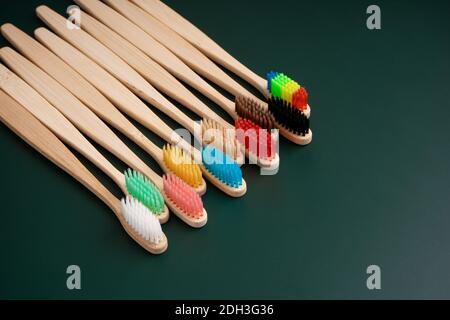 Ein Set umweltfreundlicher antibakterieller Zahnbürsten aus Bambusholz auf dunkelgrünem Hintergrund. Umwelttrends. Stockfoto