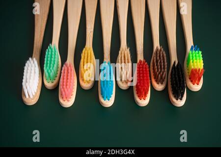 Ein Set umweltfreundlicher antibakterieller Zahnbürsten aus Bambusholz auf dunkelgrünem Hintergrund. Umwelttrends. Stockfoto