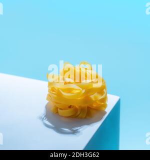 Pasta-Kunst mit Tagliatelle auf blauem Hintergrund Stockfoto