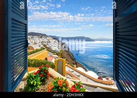 Blick durch ein offenes Fenster auf die Ägäis, Caldera und die Stadt Oia und Thira auf der Insel Santorini Griechenland. Stockfoto
