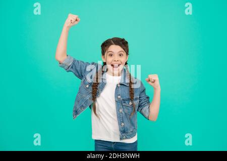 Glückliches Kind feiern Sieg machen siegreiche Geste halten Fäuste angehoben blauen Hintergrund, Gewinner. Stockfoto