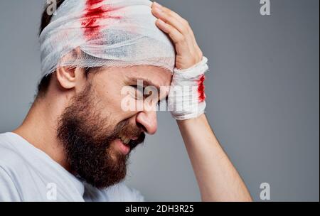 Ein Mann mit einem verbundenen Kopf Blut Reanimation Operationsmodell Gaze auf seinem Arm Stockfoto