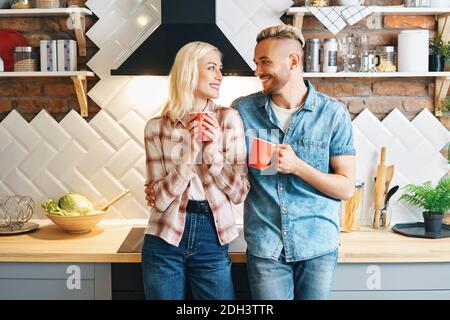 Junge glückliche Paar trinken Kaffee am Morgen und genießen Die Gesellschaft von einander in der Küche zu Hause Stockfoto
