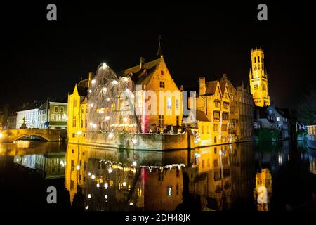 Historisches Stadtzentrum in Brügge bei Nacht, Belgien. Weihnachtliche festliche Dekoration. Alte mittelalterliche Gebäude spiegeln sich im Wasser. Zauberhafte Winterzeit. Stockfoto