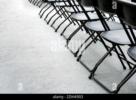Eine Gruppe leerer Klappstühle, die in einer Reihe in einem Konferenzraum angeordnet sind. Speicherplatz kopieren. Grauer Hintergrund Stockfoto