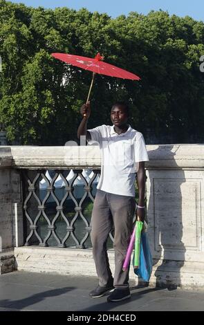 KEIN WEB/KEINE APPS - EIN junger Migrant aus Senegal verkauft am 24. Juli 2017 Regenschirme an Touristen auf einer Brücke im Zentrum Roms. Die meisten afrikanischen Migranten haben die Aufnahmezentren verlassen, um einige Tage vor ihrer Weiterreise nach Norden hier zu bleiben, einige wissen nicht, dass die Grenzen für sie geschlossen sind, andere sind entschlossen, es nach gescheiterten Überquerung erneut zu versuchen. Jeder hier hat Wochen, Monate oder sogar Jahre auf der Straße verbracht, Trekking durch die Wüste, durch Libyen und über das Mittelmeer. Foto von Eric Vandeville/ABACAPRESS.COM Stockfoto