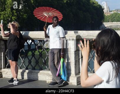 KEIN WEB/KEINE APPS - EIN junger Migrant aus Senegal verkauft am 24. Juli 2017 Regenschirme an Touristen auf einer Brücke im Zentrum Roms. Die meisten afrikanischen Migranten haben die Aufnahmezentren verlassen, um einige Tage vor ihrer Weiterreise nach Norden hier zu bleiben, einige wissen nicht, dass die Grenzen für sie geschlossen sind, andere sind entschlossen, es nach gescheiterten Überquerung erneut zu versuchen. Jeder hier hat Wochen, Monate oder sogar Jahre auf der Straße verbracht, Trekking durch die Wüste, durch Libyen und über das Mittelmeer. Foto von Eric Vandeville/ABACAPRESS.COM Stockfoto