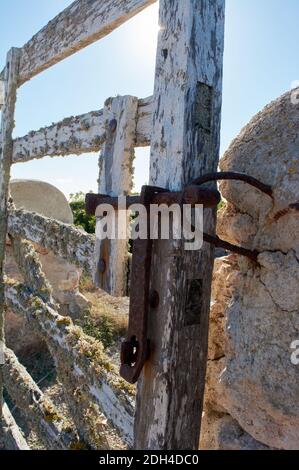 Detail von Eisen-Riegel auf typische Holztür, mit Flechten, auf Steinmauer neben dem Weg, mit schönen blauen Himmel über mediterranen Wald, mallorca Stockfoto