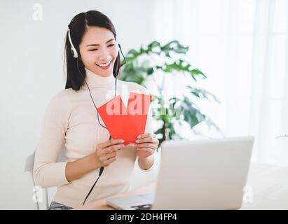 Glücklich asiatische junge Frau machen Abstand Video Anruf und zeigen Roter Umschlag zur Feier des chinesischen Neujahrjahres Stockfoto