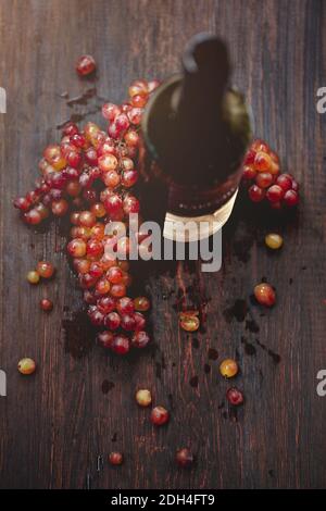Flasche Wein und Traube auf Holzgrund Stockfoto
