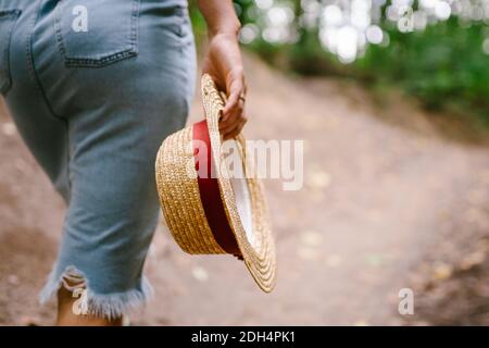 Outdoor-Foto von spannenden Mädchen chillen in einem schönen Wald. Fröhliche junge hübsche Frau in Vintage Strohhut posiert im Park Stockfoto