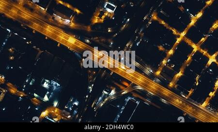 Top-down-Nachtautobahn mit beleuchteten Stadtstraßen Luftaufnahme. Philippinen Innenstadt Stadtbild mit moderner Architektur von Wolkenkratzern Gebäude. Filmische Stadtstraße an Laternen Lichter Drohne erschossen Stockfoto