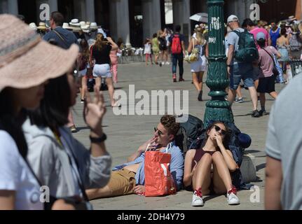 KEINE WEB/KEINE APPS - am 12. August 2017 auf dem Markusplatz, dem Zentrum der touristischen Schwerkraft in Venedig, Italien, lausige Touristen. Hier ist es verboten zu sitzen. Die Stadt Venedig, die von Touristen überfallen wird, riskiert, ‘D„Inselland am Meer“ zu werden. Die meisten Venezianer verachten die giganten Kreuzfahrtschiffe, die jeden Tag durch den Giudecca-Kanal schaufeln, Dämpfe aussenden, die zu Erosion des Watts und Sedimentverlust führen, bevor sie Tausende von Menschen in das historische Zentrum verschleppen. Ob durch Selfie-Stöcke, laute Wheelie-Koffer oder Leute, die auf einer der 391 Brücken schnüffeln, Venedigs Verachtung gegenüber irritiert Stockfoto