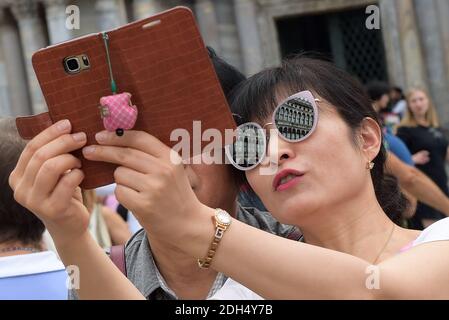 KEINE WEB/KEINE APPS - Asiatische Touristen machen Selfies auf dem Markusplatz, dem Zentrum der touristischen Schwerkraft in Venedig, Italien am 12. August 2017. Die Stadt Venedig, die von Touristen überfallen wird, riskiert, ‘D„Inselland am Meer“ zu werden. Die meisten Venezianer verachten die giganten Kreuzfahrtschiffe, die jeden Tag durch den Giudecca-Kanal schaufeln, Dämpfe aussenden, die zu Erosion des Watts und Sedimentverlust führen, bevor sie Tausende von Menschen in das historische Zentrum verschleppen. Ob durch Selfie-Stöcke, laute Wheelie-Koffer oder Leute, die auf einer der 391 Brücken schnüffeln, Venedigs Verachtung gegenüber den 30 Millionen V irritiert Stockfoto