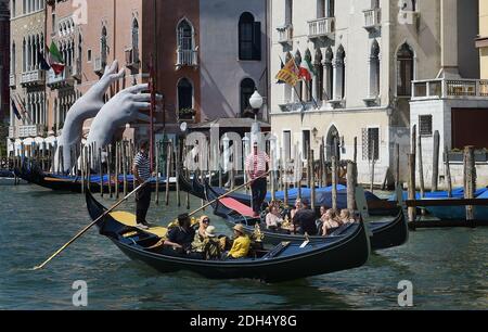 KEINE WEB/KEINE APPS - Touristen in Gondeln auf dem Canal Grande in Venedig, Italien am 12. August 2017. Links: Skulptur des Künstlers Lorenzo Quinn. Die Stadt Venedig, die von Touristen überfallen wird, riskiert, ‘D„Inselland am Meer“ zu werden. Die meisten Venezianer verachten die giganten Kreuzfahrtschiffe, die jeden Tag durch den Giudecca-Kanal schaufeln, Dämpfe aussenden, die zu Erosion des Watts und Sedimentverlust führen, bevor sie Tausende von Menschen in das historische Zentrum verschleppen. Ob durch Selfie-Stöcke, laute Wheelie-Koffer oder Leute, die auf einer der 391 Brücken schnüffeln, Venedigs Verachtung gegenüber den 30 Millionen VI Stockfoto