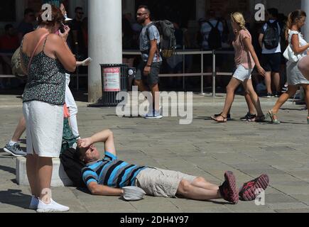 KEINE WEB/KEINE APPS - am 12. August 2017 auf dem Markusplatz, dem Zentrum der touristischen Schwerkraft in Venedig, Italien, lausige Touristen. Hier ist es verboten zu sitzen. Die Stadt Venedig, die von Touristen überfallen wird, riskiert, ‘D„Inselland am Meer“ zu werden. Die meisten Venezianer verachten die giganten Kreuzfahrtschiffe, die jeden Tag durch den Giudecca-Kanal schaufeln, Dämpfe aussenden, die zu Erosion des Watts und Sedimentverlust führen, bevor sie Tausende von Menschen in das historische Zentrum verschleppen. Ob durch Selfie-Stöcke, laute Wheelie-Koffer oder Leute, die auf einer der 391 Brücken schnüffeln, Venedigs Verachtung gegenüber irritiert Stockfoto