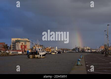 Ein geschwollener schlammiger Fluss Tiber fließt durch Fiumicino Hafen kurz nach einem schweren Sturm. Einige Fischerboote zurück von der Arbeit. Bläulicher Himmel. Sonnenstrahl Stockfoto