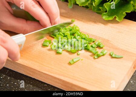 Gehackte grüne Zwiebel und die Hand mit Messer Stockfoto