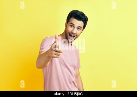 Glücklicher lächelnder Mann, der auf Sie zeigt und auf die Kamera schaut Auf gelbem Hintergrund Stockfoto