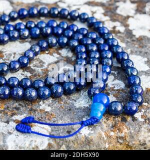 Eine Nahaufnahme von blauen mala-Perlen (Lapislazuli) auf Stein - Yoga und Meditation Zubehör Stockfoto