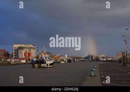 Ein geschwollener schlammiger Fluss Tiber fließt durch Fiumicino Hafen kurz nach einem schweren Sturm. Einige Fischerboote zurück von der Arbeit. Bläulicher Himmel. Sonnenstrahl Stockfoto