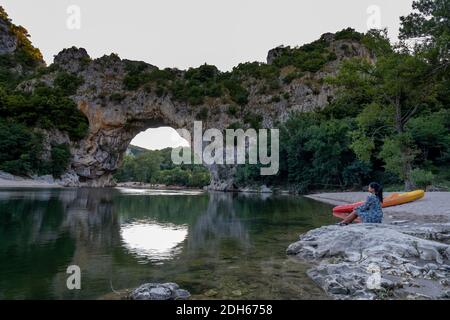 Frau am Strand am Fluss in der Ardeche Frankreich Pont d Arc, Ardeche Frankreich, Blick auf den Narural Bogen in Vallon Pont d'Arc in Ar Stockfoto