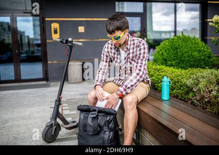 Handsome Hipster-Stil bärtigen Mann arbeitet online Freiberufler, zieht Laptop mit Rucksack und Elektroroller, aktive lifestyl Stockfoto