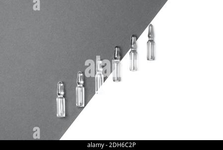 Linie von Ampullen für Injektionen auf trendigen grauen und isolierten weißen Hintergrund. Medizin, Gesundheitswesen und Pharmazie Konzept. Color 2021 Konzept. Flache Lay s Stockfoto