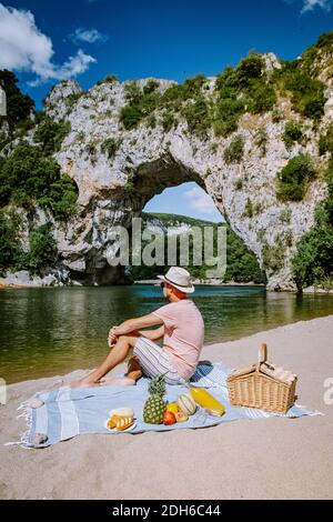 Paar am Strand am Fluss in der Ardeche Frankreich Pont d Arc, Ardeche Frankreich, Blick auf den Narural Bogen in Vallon Pont d'Arc in EINEM Stockfoto