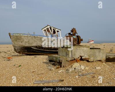 Ein altes, zerstörtes Fischerboot am Dungeness Beach, England. Dieses Boot verließ nun verlassen und hoch und trocken. Die verrosteten Reste eines Motors, der vorne zu sehen ist. Stockfoto
