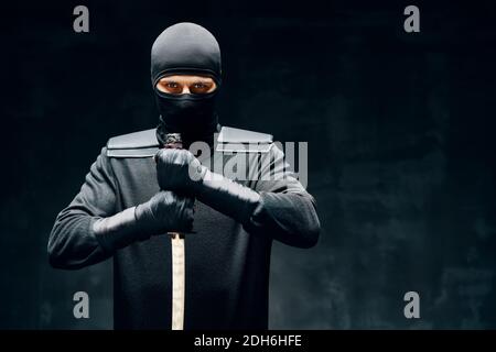 Kampf Ninja posiert mit einem Schwert über schwarzem Hintergrund Stockfoto