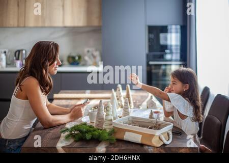 Kleines Mädchen macht Weihnachtsbaum Kegel Handwerk und Dekoration mit Knöpfen, Garne Stockfoto