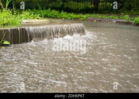 Der Wasserstrom fließt hinunter in die Fußgängerzone. Regnerisches Herbstwetter. Starker Regen. Straßenszenen im Regen. Stockfoto