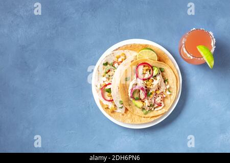 Mexikanische Tacos, Tortillas mit gezogenem Hühnerfleisch, Avocado, Mais und Zwiebel, mit dem Paloma-Cocktail, Schuss über dem Kopf Stockfoto