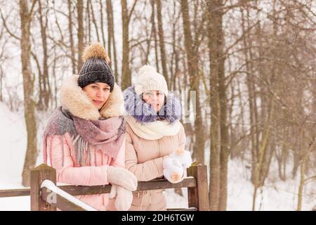 Zwei Mädchen laufen in einem Winterpark im Schnee. Schwestern auf dem Hintergrund von verschneiten Bäumen Stockfoto