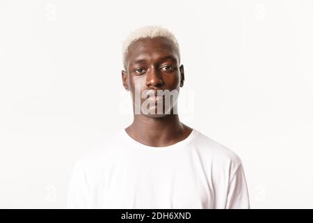 Nahaufnahme von seriösen schönen afroamerikanischen blonden stilvollen Kerl, Blick auf die Kamera entschlossen und ruhig, stehend weiß backgroun Stockfoto