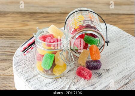 Gelee süße Süßigkeiten verschiedener Farben auf hölzern verstreut Hintergrund aus dem Glas Stockfoto