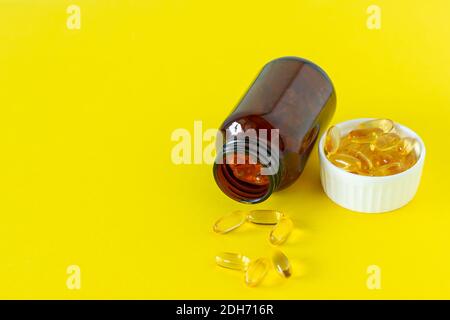 Fischöl-Kapseln auf gelbem Hintergrund, Vitamin D, Omega-Ergänzung, selektiver Fokus Stockfoto