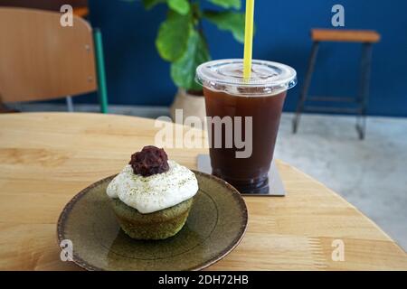 Matcha Grüner Tee Cupcake serviert mit Iced Black Americano Kaffee Auf Holztisch Stockfoto