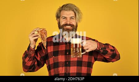 Happy bärtigen Mann mit Bier und Pizza. italienisches Essen. italien ist hier. Kerl in der Bar Bier trinken und Pizza essen. Prost. Ein Glas Bier und Pizza. Fußball im Fernsehen. Fast Food. Stockfoto