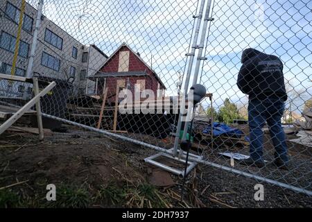 Portland, USA. Dezember 2020. Ein Arbeiter steht hinter Fechten, als Polizeibeamte versuchen, den Bereich der Demonstranten, die das Rote Haus auf der Mississippi Straße in Portland, Oregon, bewachen, am 8. Dezember 2020 während eines Versuchs, das Grundstück zu vertreiben, zu sichern und zu räumen. Aktivisten zelteten seit September vor dem Haus in der Hoffnung, die dort lebende Familie der Schwarzen und Indigenen zu erhalten, nachdem ein Richter des Landkreises Multnomah die Räumung genehmigt hatte. (Foto: Alex Milan Tracy/Sipa USA) Quelle: SIPA USA/Alamy Live News Stockfoto