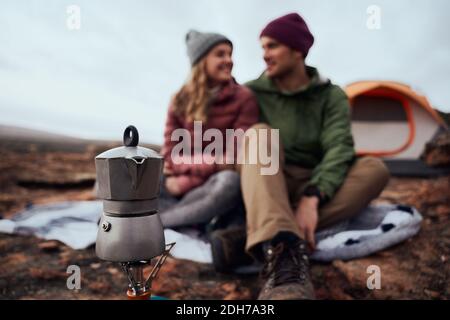 Nahaufnahme des Kessels auf dem Gasherd während des Campens mit einem Lächeln Paar schaut einander im Winter an - jung abenteuerlich Paar Camping und machen Stockfoto