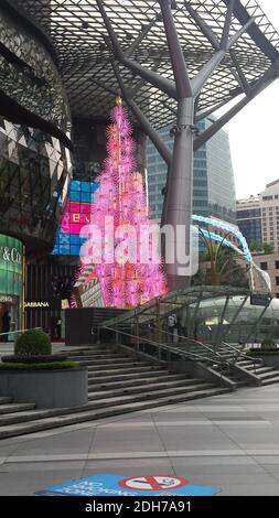 SINGAP, SINGAPUR - 11. Nov 2019: Ein elektrischer Weihnachtsbaum in rosa, beleuchtet am Tag vor einer Mall für Top-Marken auf Orchard Road, S Stockfoto